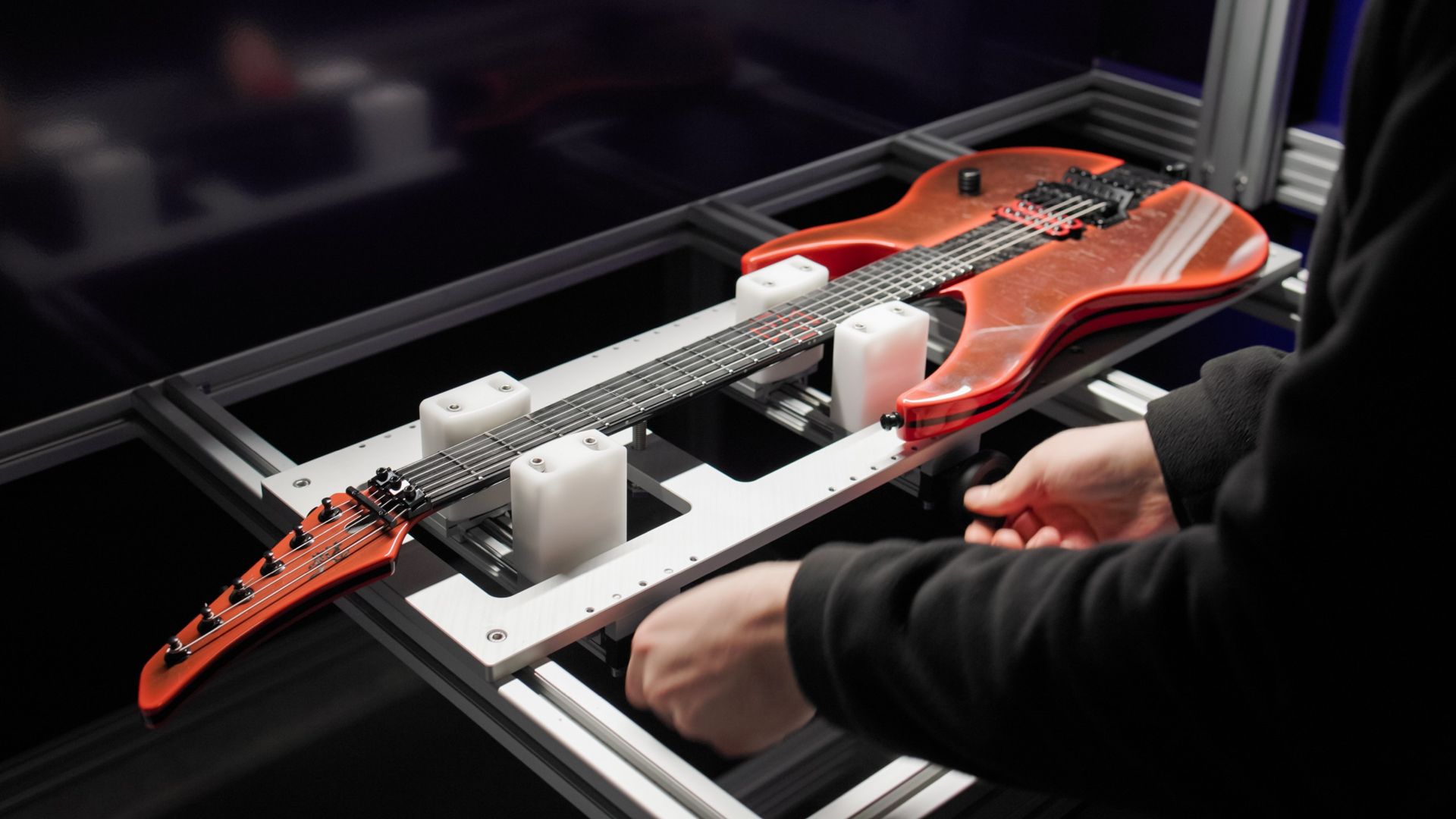 Operator positioning a guitar on the inspection rig